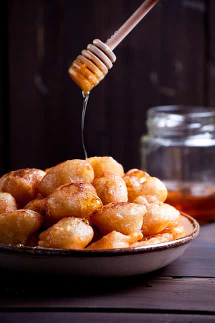Plate of homemade greek donuts loukoumades with honey and cinnamon