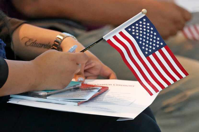 A citizenship candidate holds an American flag as she awaits the start of a naturalization...