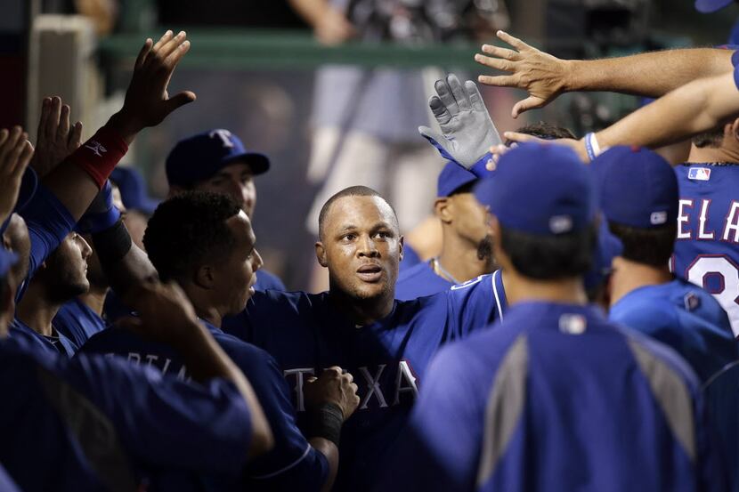 Texas Rangers' Adrian Beltre, center, is greeted by teammates after he scored on a single...