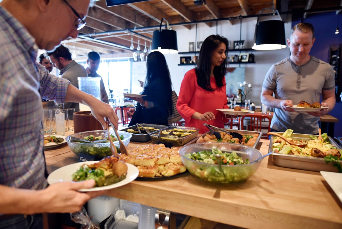 Seema Shah, left, and Jeff Kempf serve themselves food during a fundraising dinner for the...