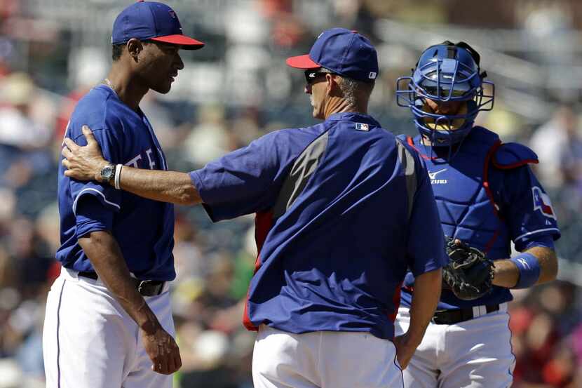 Texas Rangers pitching coach Mike Maddux, center, talks with starting pitcher Alexi Ogando,...
