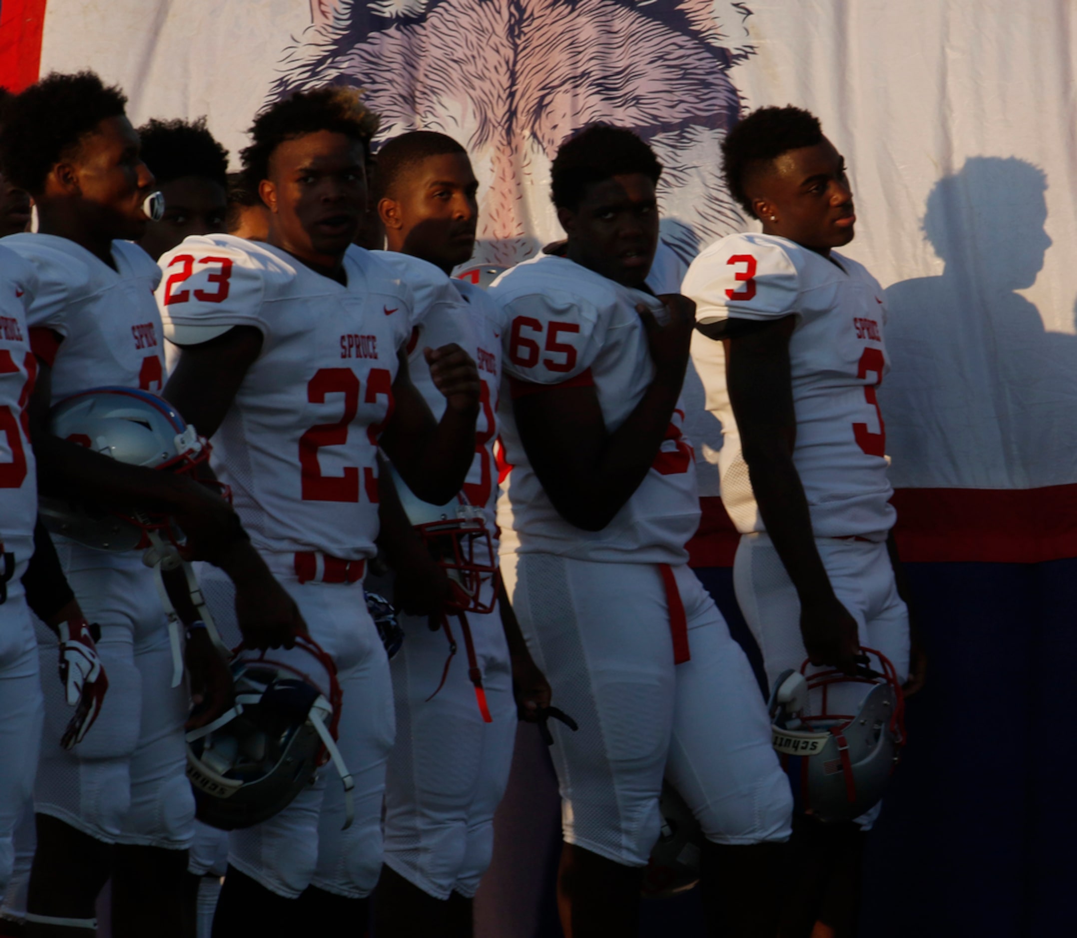 Spruce receiver Mardio Trigg (3) reflects as he pauses with teammates for the playing of the...