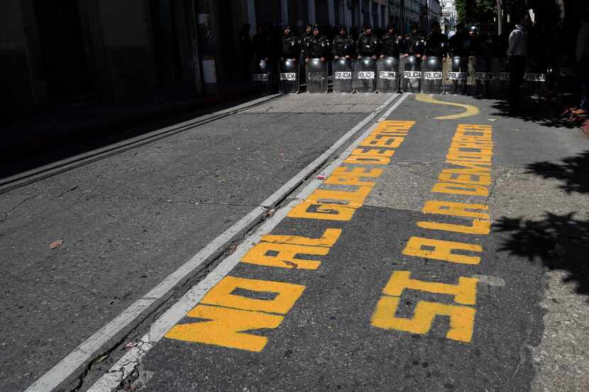 A message on the street reads in Spanish "No to the Coup, Yes to Democracy," as police stood...