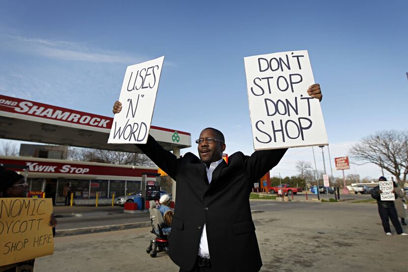 Curtis Lee holds up signs as he joins others in protesting outside a Kwik Stop station...