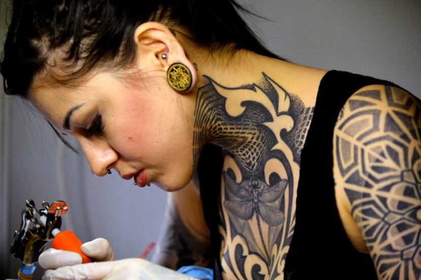 A tattoo artist works during the Female Artists Tattoo Convention on March 14, 2015 in Rome. 