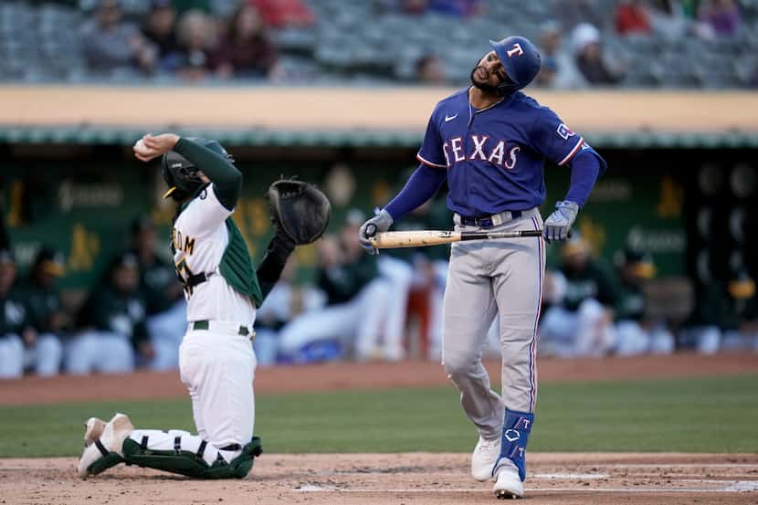 Texas Rangers' Leody Taveras, right, reacts after striking out against the Oakland Athletics...