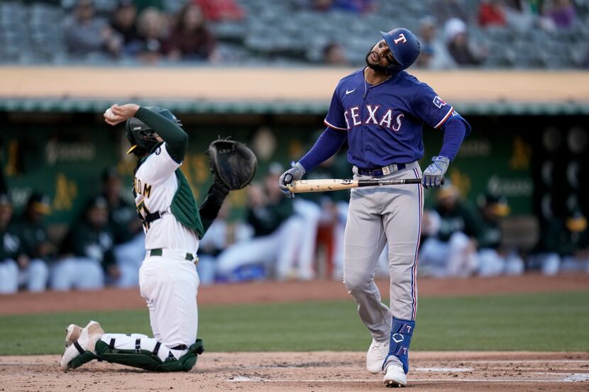 Texas Rangers' Leody Taveras, right, reacts after striking out against the Oakland Athletics...
