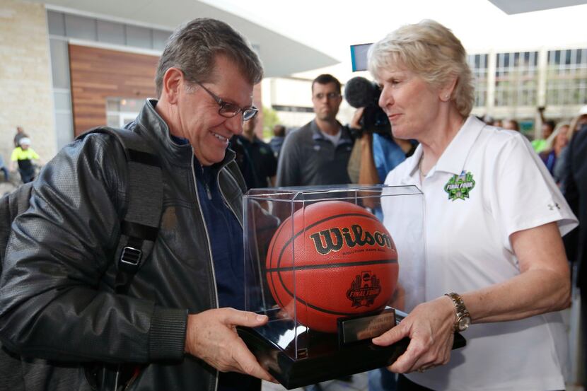 UConn Huskies women basketball team head coach Geno Auriemma, left, receives a game ball...