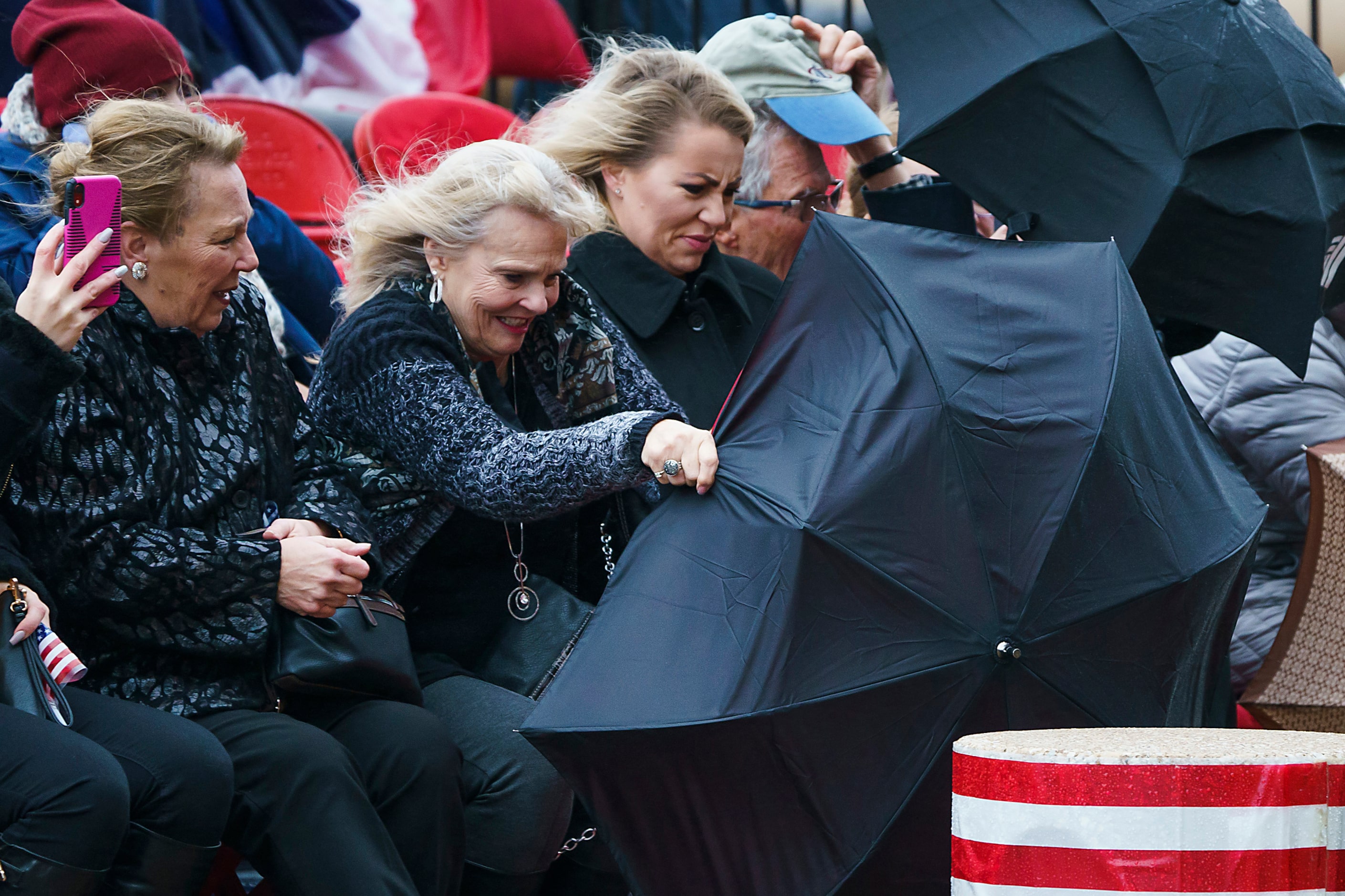 Spectators struggle to hold onto their umbrellas as strong winds buffet an 11th hour...