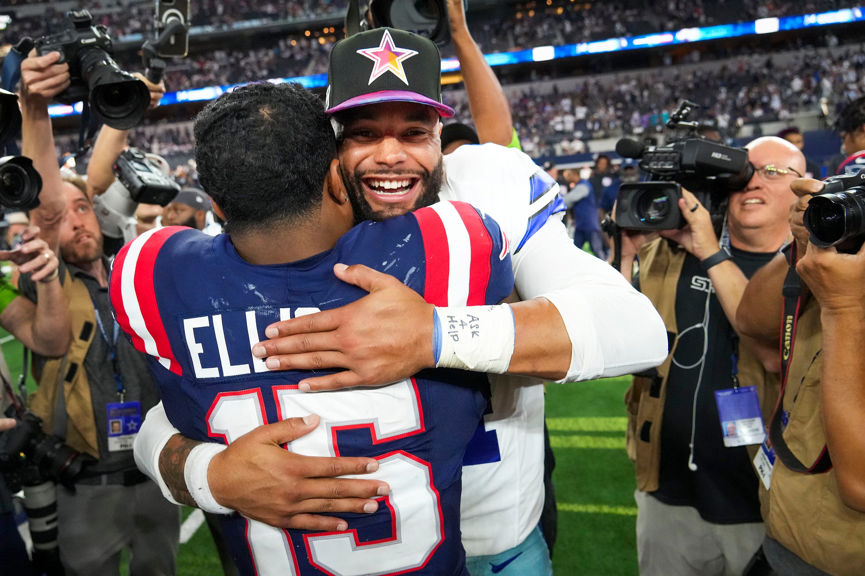 Dallas Cowboys quarterback Dak Prescott (4) hugs New England Patriots running back Ezekiel...