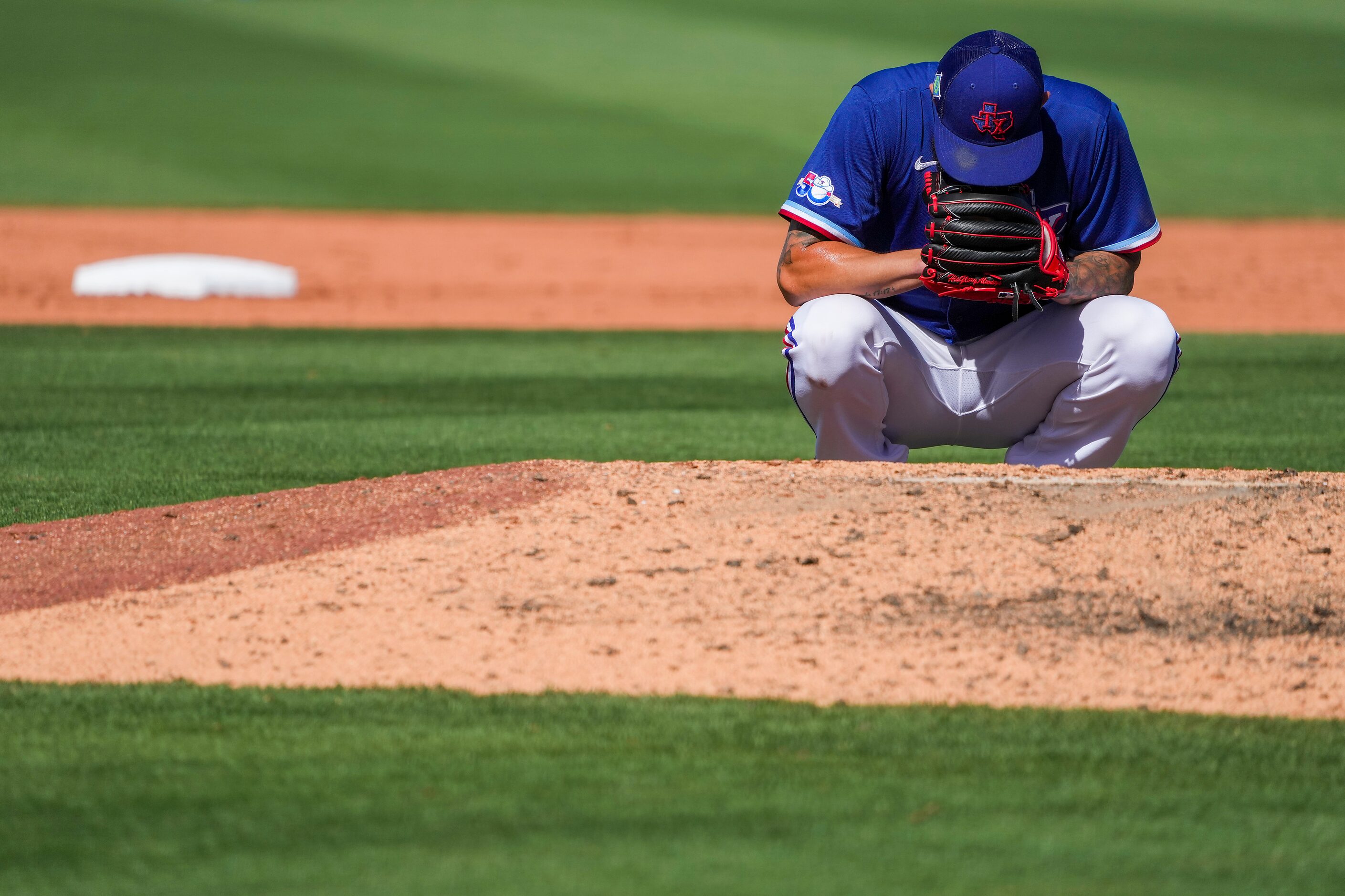 Texas Rangers pitcher Joe Barlow kneels behind the mound before pitching during the ninth...