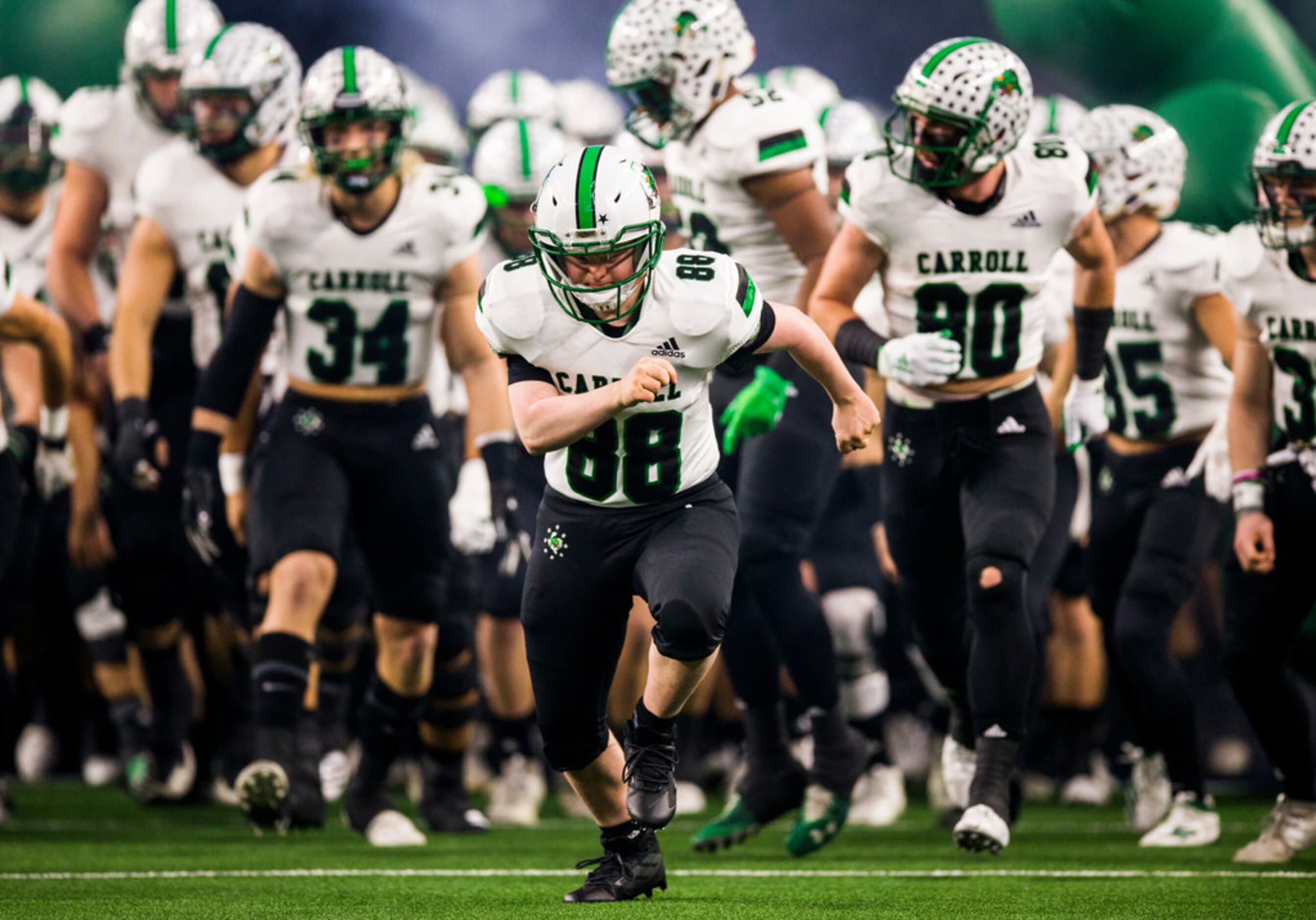 Southlake Carroll football players run out on the field before a Class 6A Division I...