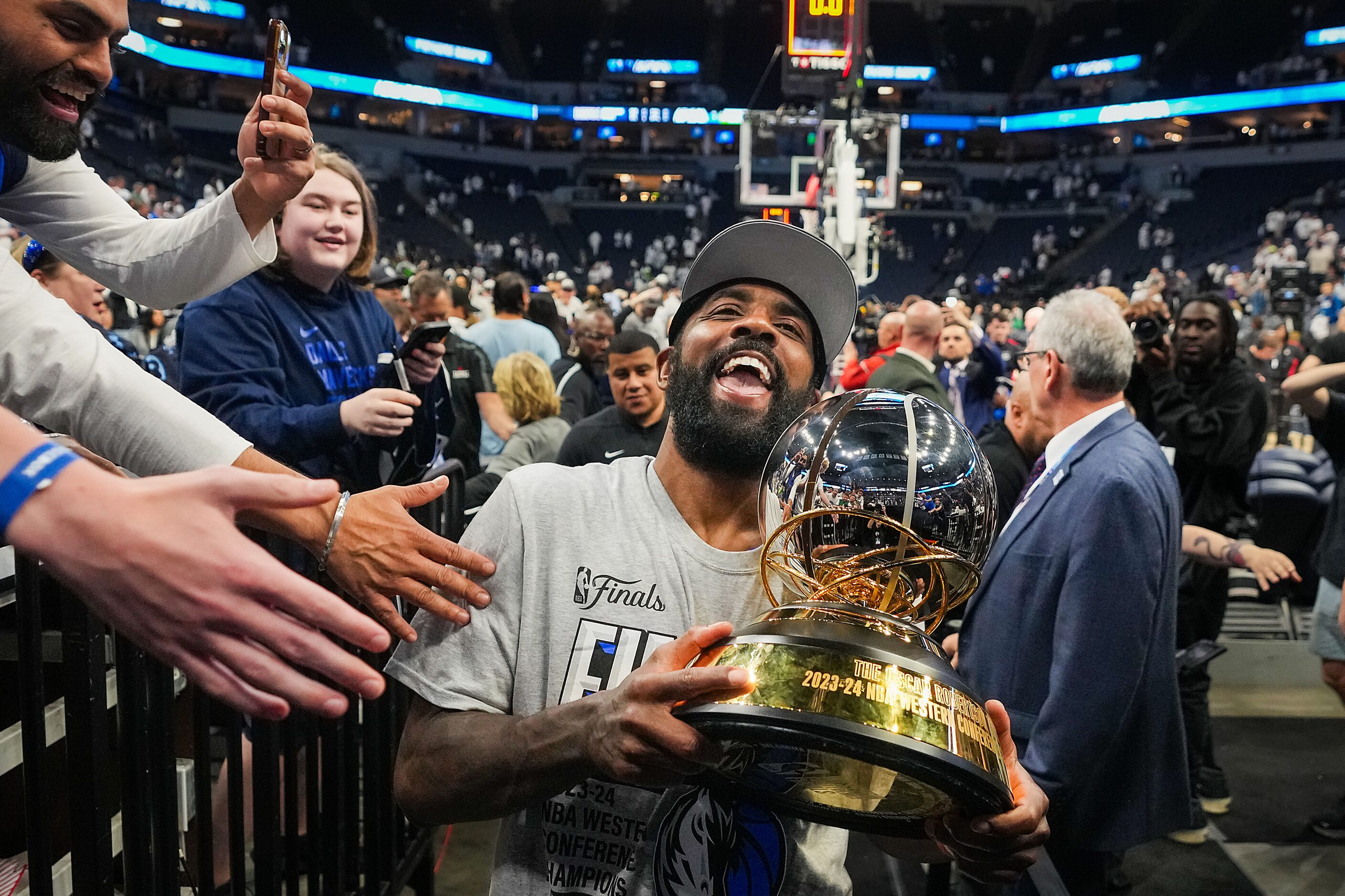 Dallas Mavericks guard Kyrie Irving celebrates as he carries the trophy from the court after...