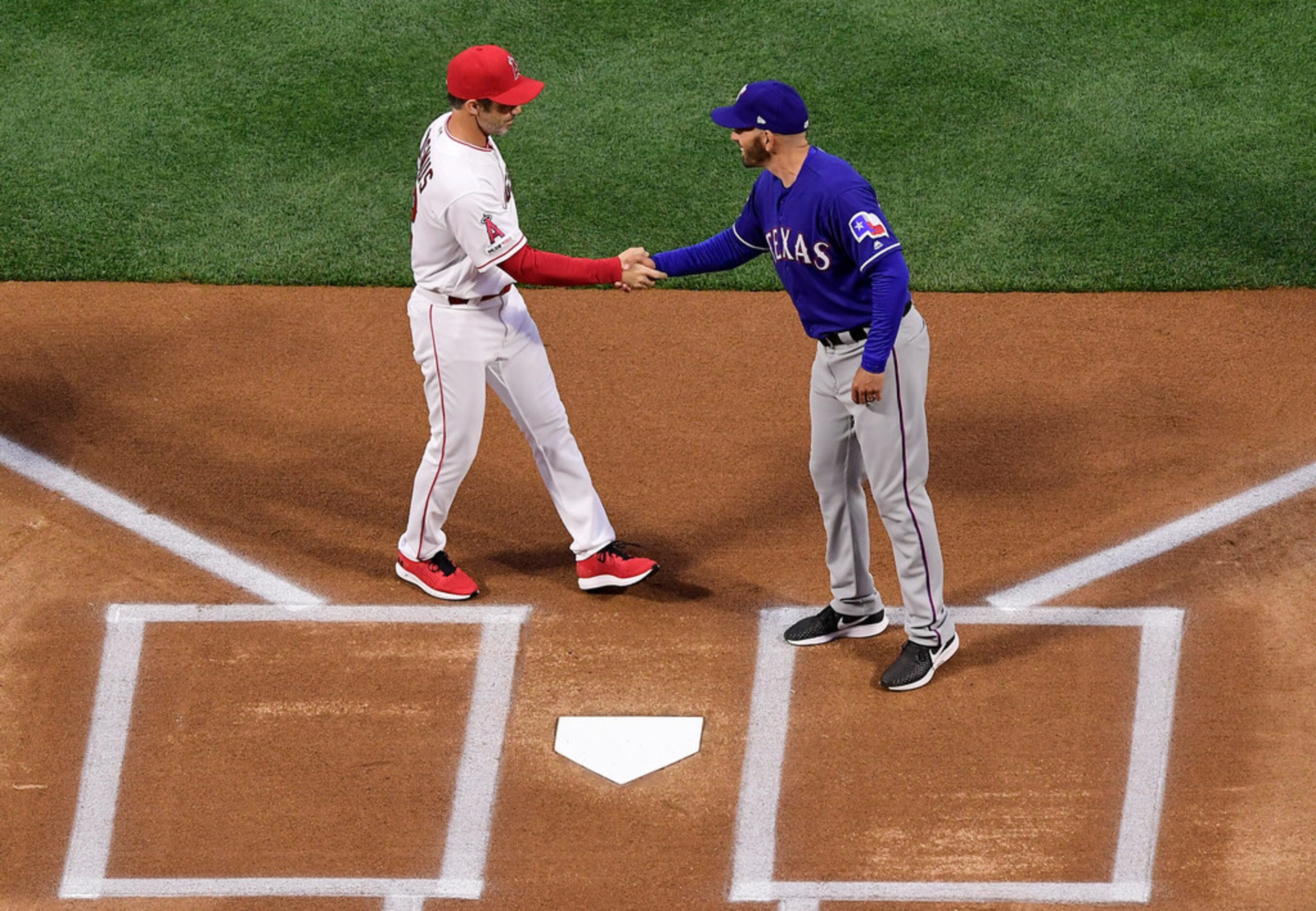 Los Angeles Angels manager Brad Ausmus, left, greets Texas Rangers manager Chris Woodward...