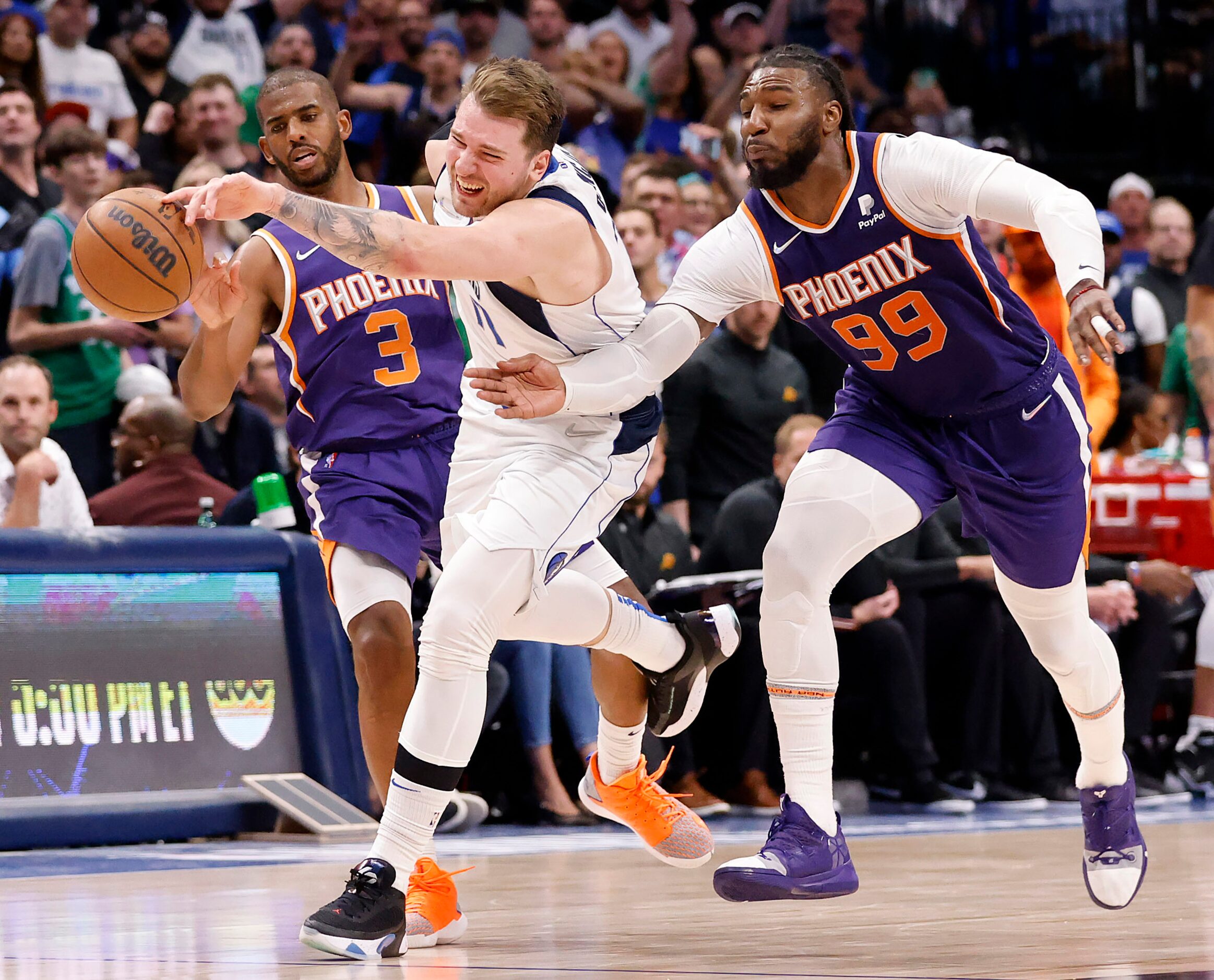 Dallas Mavericks guard Luka Doncic (77) is fouled as he is double teamed by Phoenix Suns...