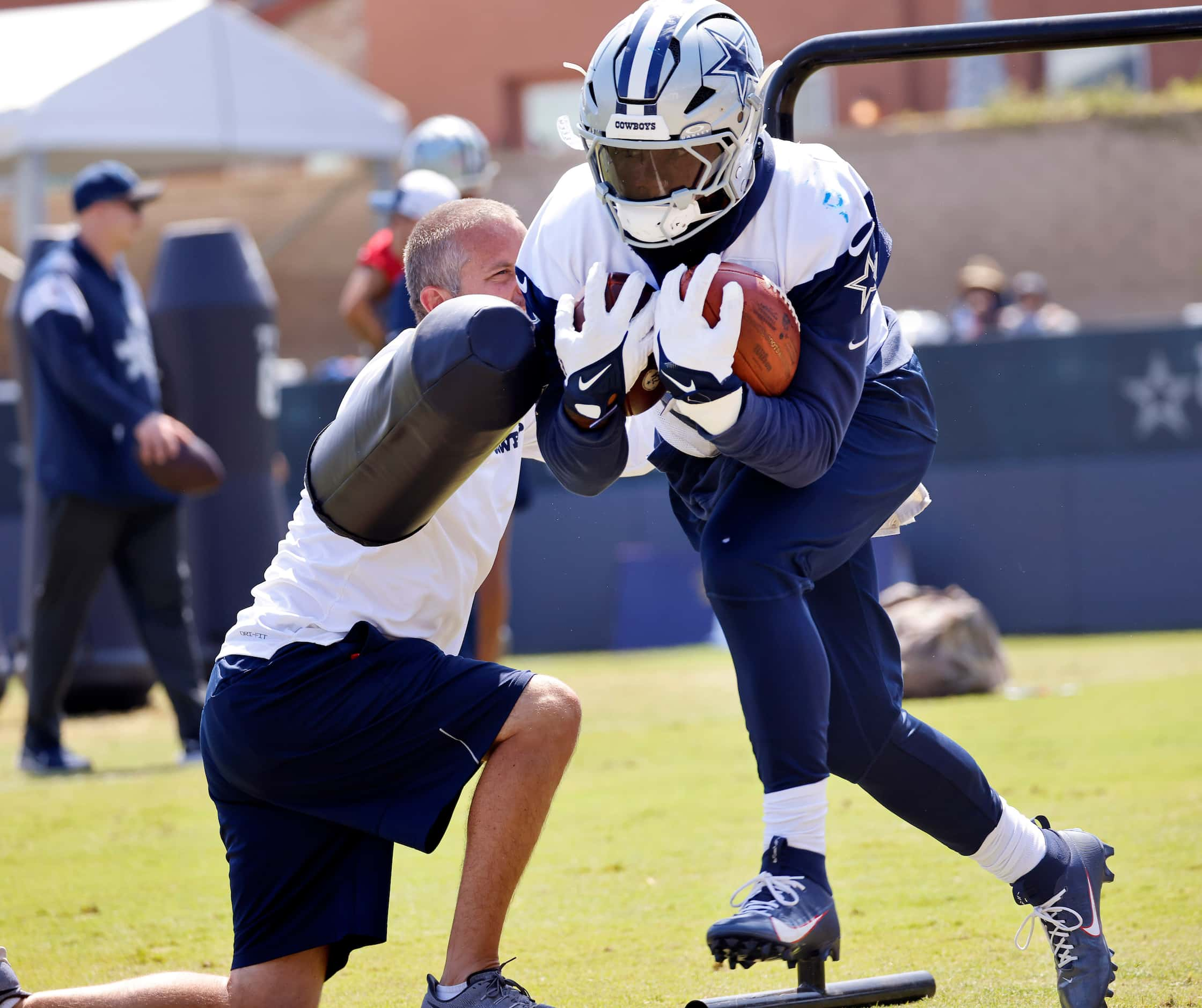 Carrying a pair of footballs, Dallas Cowboys running back Ezekiel Elliott (15) is pounded...