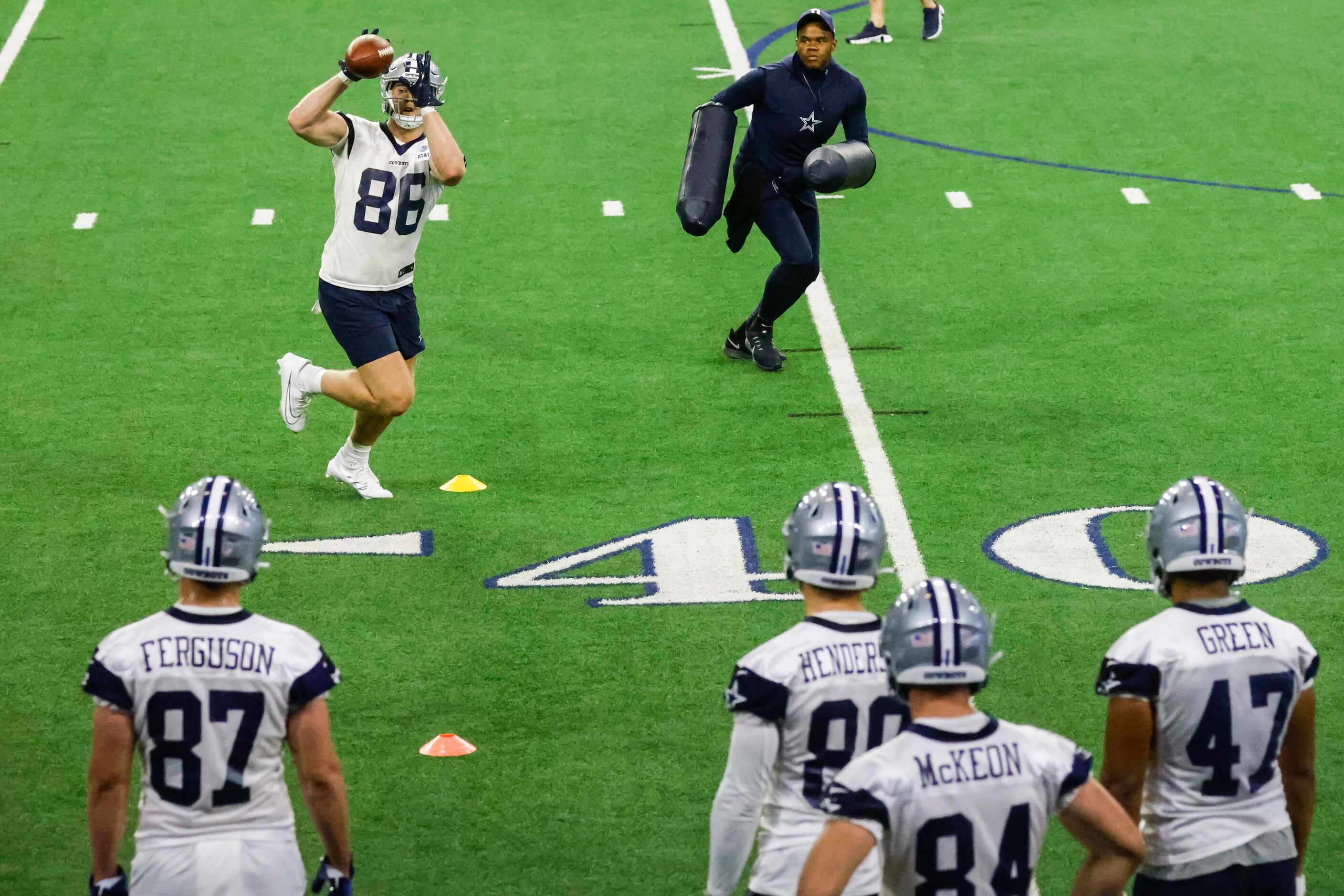 Dallas Cowboys tight end Luke Schoonmaker (left) receives the ball past tight end coach...