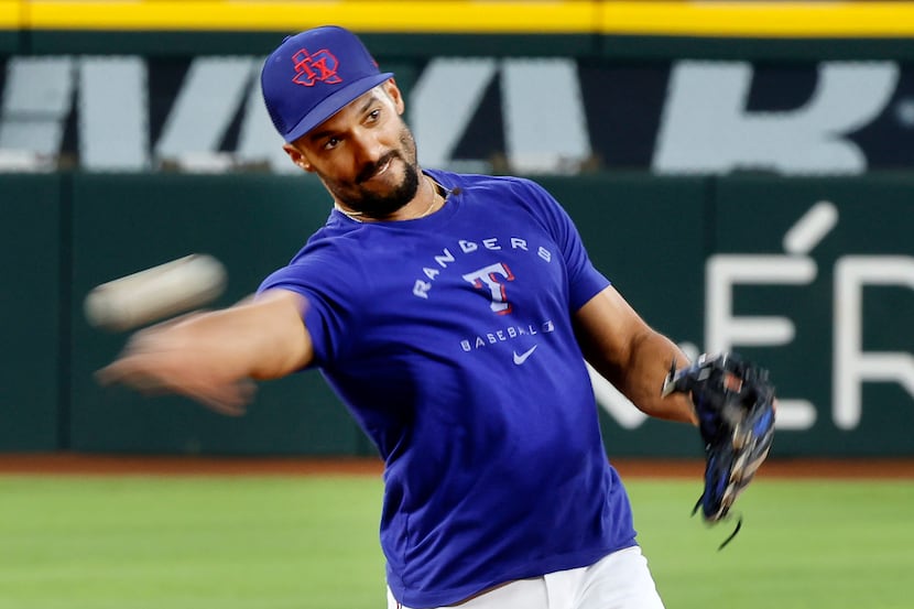 Texas Rangers second baseman Marcus Semien whips a throw to first during fielding practice...