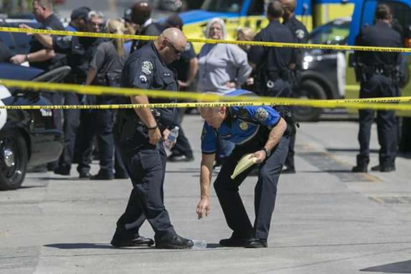  Police examine the scene where an officer was shot in the parking lot of Frank & Angieâs...