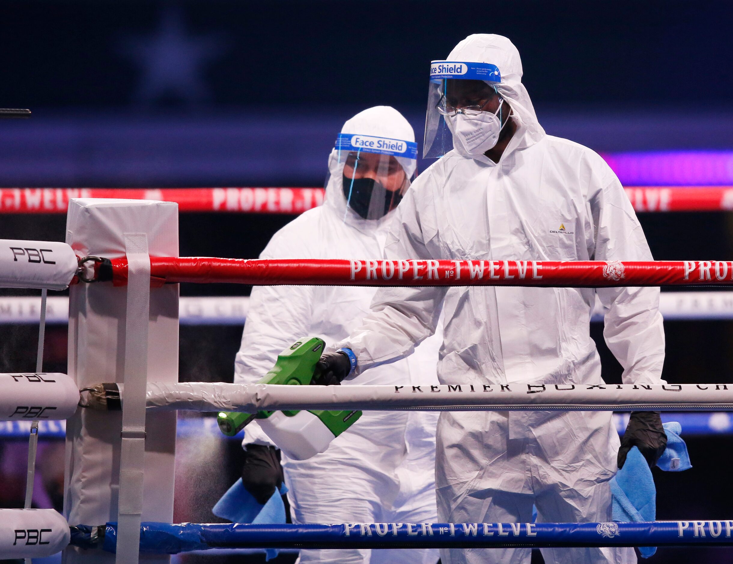 A cleaning crew in protective gear cleans the rings after a fight between Burley Brooks and...