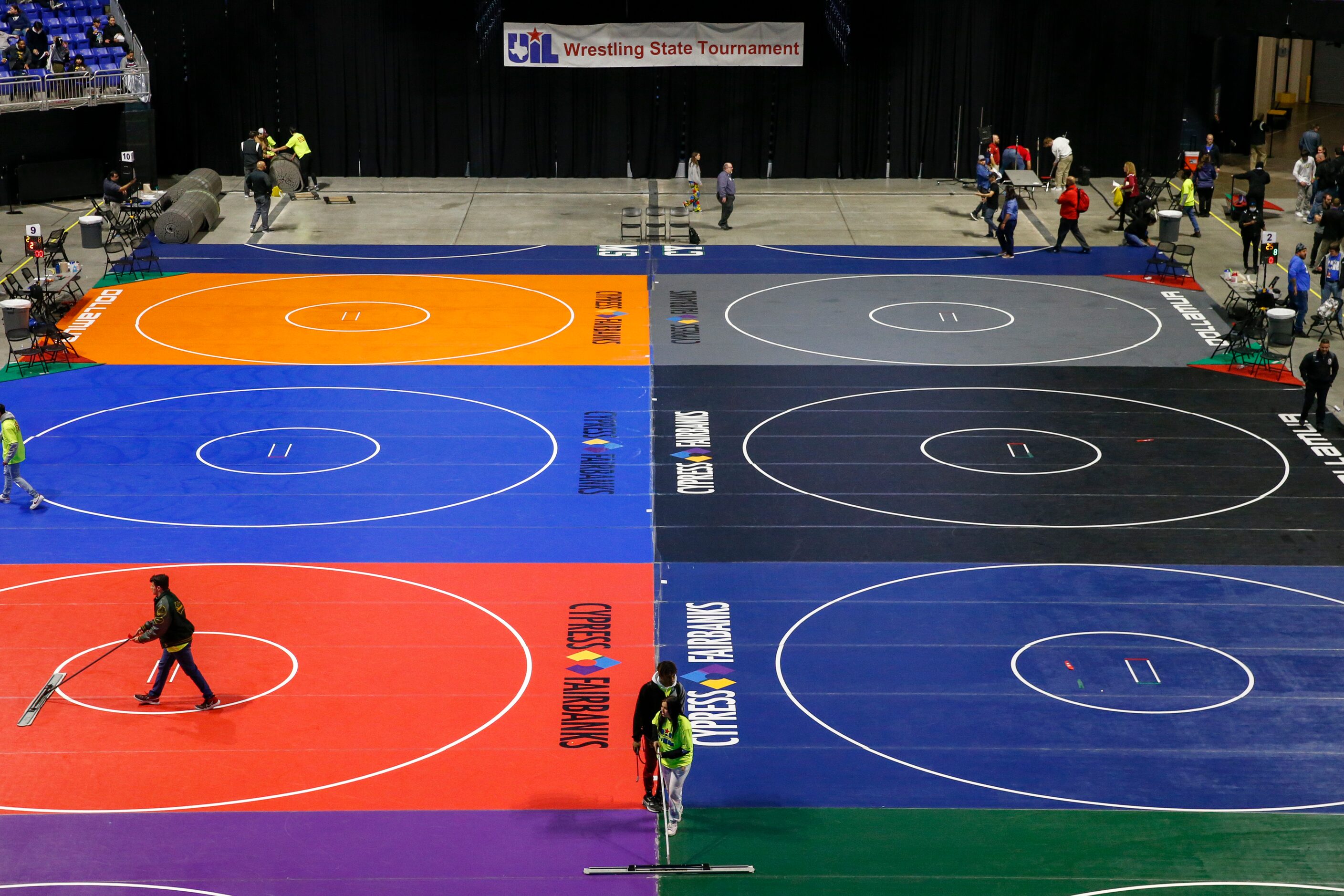 Workers clean the mats during a break at the UIL State Wrestling tournament at the Berry...