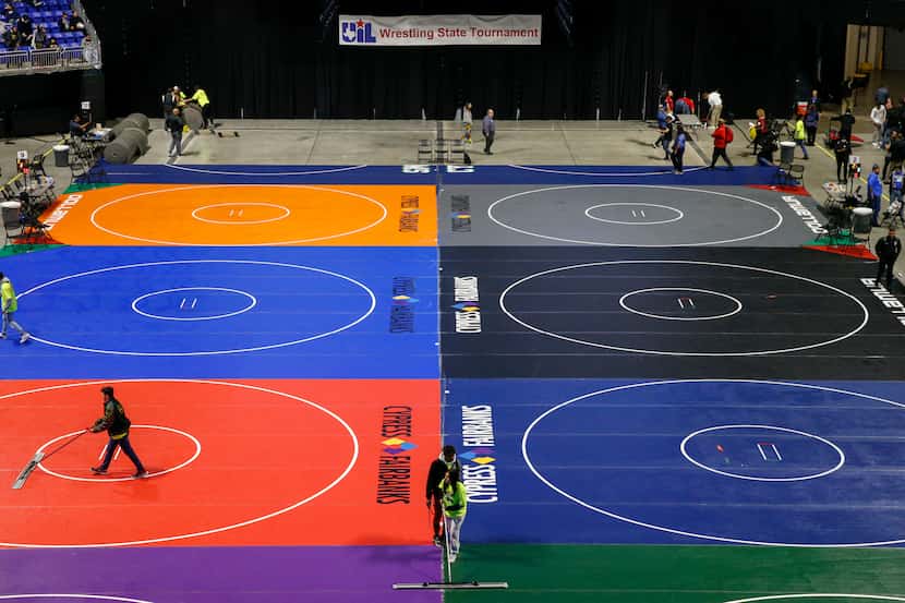 Workers clean the mats during a break at the UIL State Wrestling tournament at the Berry...