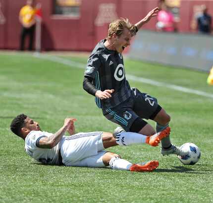 Minnesota United's Rasmus Schuler, right, is tackled by the Vancouver Whitecaps' Sean...