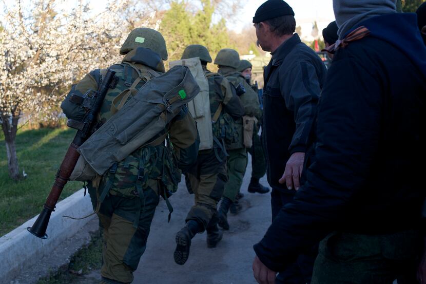 Soldiers with grenade launchers run as Pro-Russian militia members guard outside the Belbek...