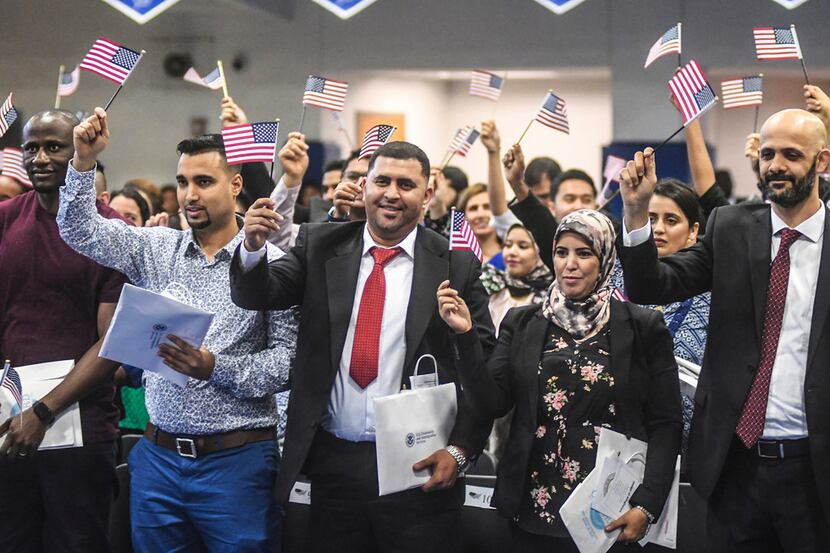 New citizens wave U.S. flags after taking the oath of citizenship during a naturalization...
