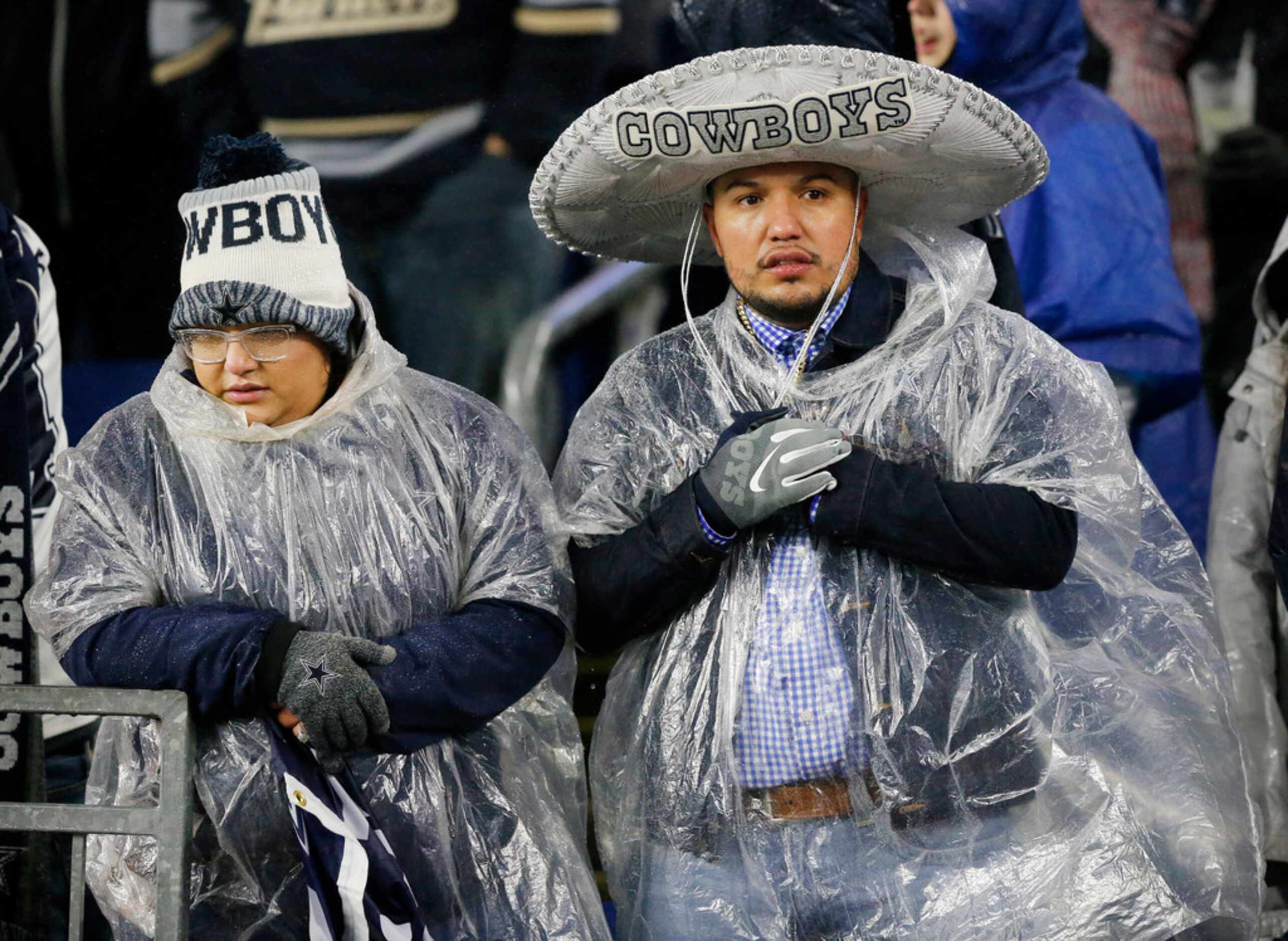 Dallas Cowboys fans try to stay warm, and dry, during the second half as the wind driven...