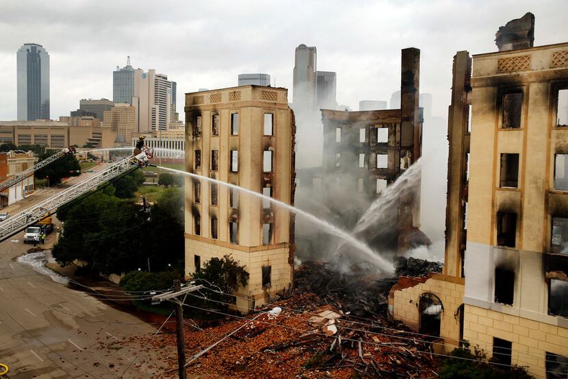 A Dallas firefighter mans an aerial hose to douse the fire at the Ambassador Hotel just...