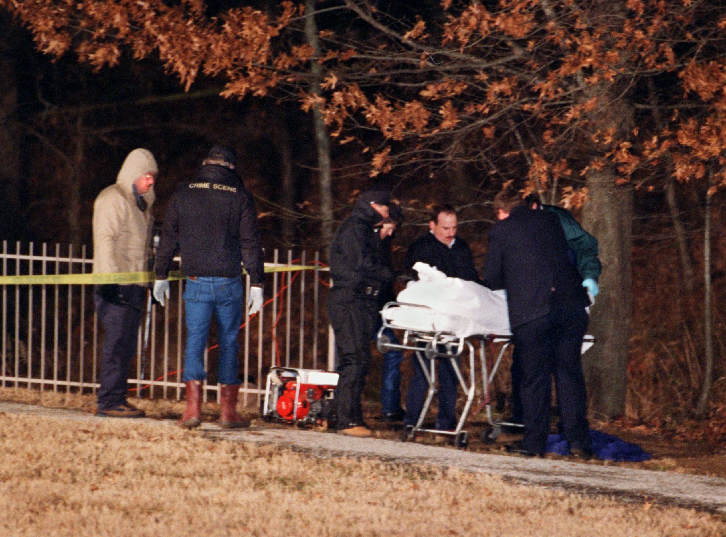 Investigators watch as personnel  from the Medical Examiner's office in Tarrant County...