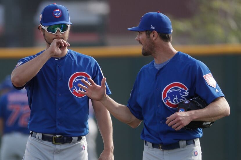Chicago Cubs' Yu Darvish talks to Cole Hamels during a spring training baseball workout...