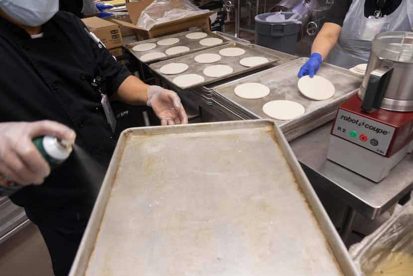 Pans are greased and then loaded with pizza dough for the next day at Parkland Memorial...