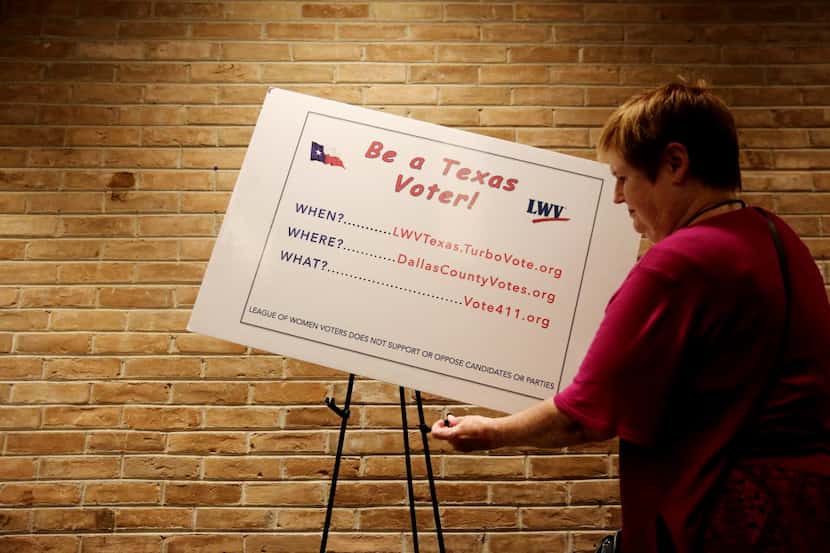 Elizabeth Walley, of Mesquite, Texas, part of the League of Women Voters, hangs a poster...