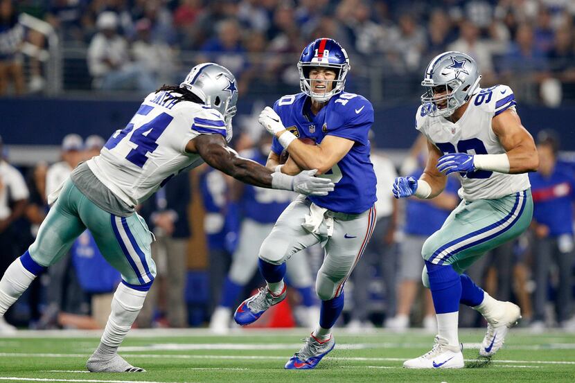 New York Giants quarterback Eli Manning (10) is hit hard and tackled by Dallas Cowboys...