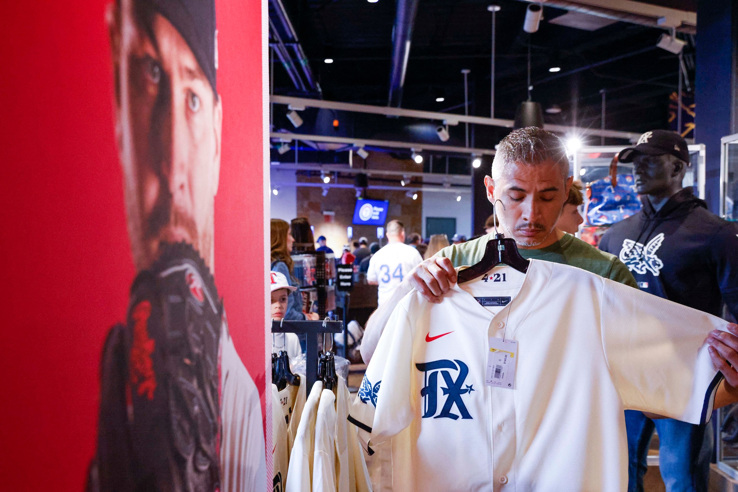 Ro Rives of Dallas area tries a Texas Rangers City Connect jersey before a baseball game...