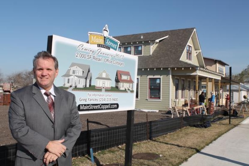 
Coppell City Manager Clay Phillips stands next to the first three office cottages in Old...