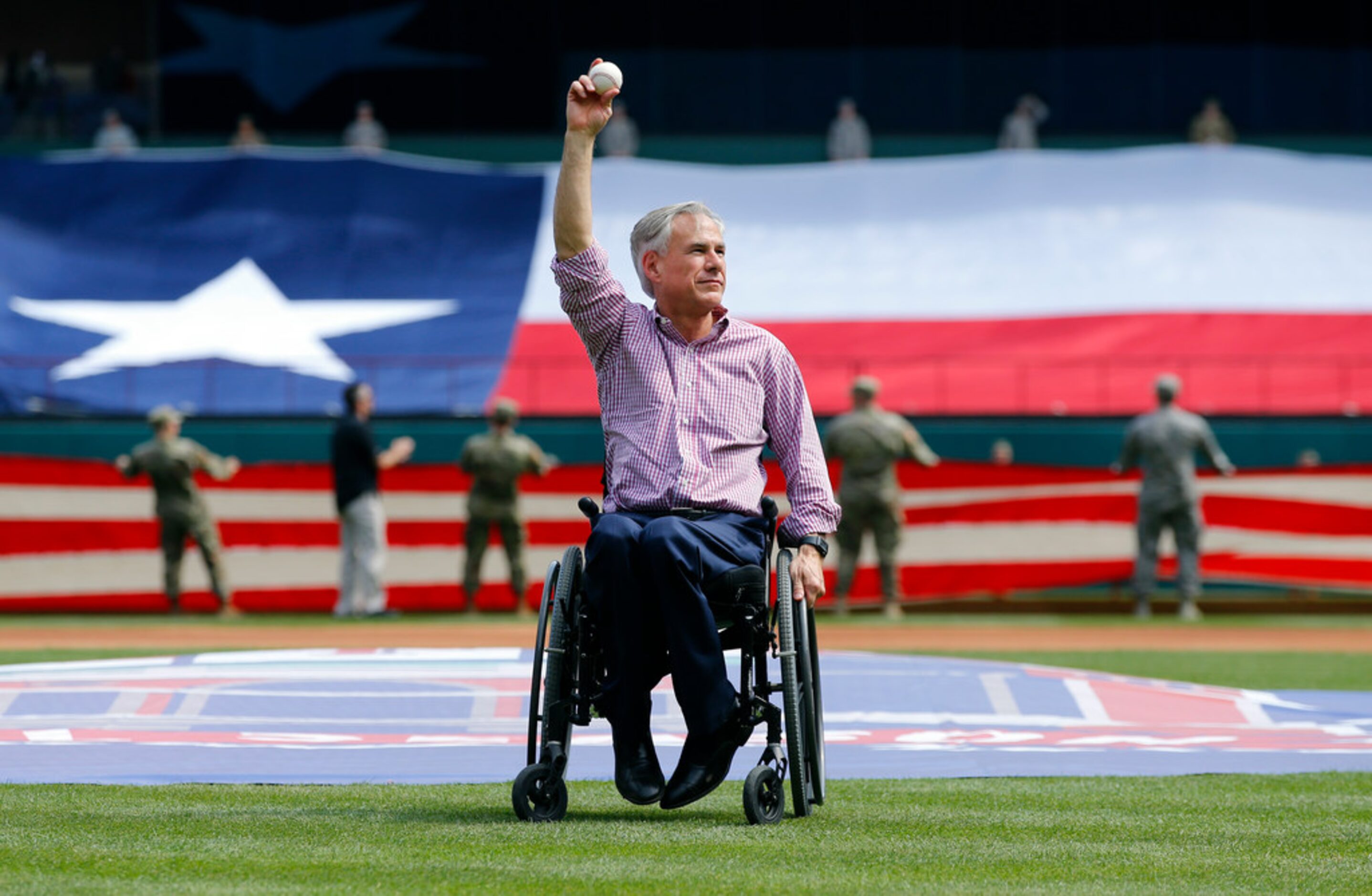 Texas governor Greg Abbott waves to the crowd before throwing out the ceremonial first pitch...