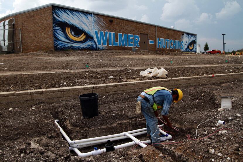 Sergio Gomez works on a water sprinkler system outside the Wilmer-Hutchins high school...