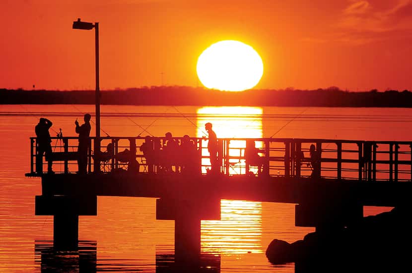 The sun sets over the fishing pier at the Isle du Bois unit at Lake Ray Roberts during...