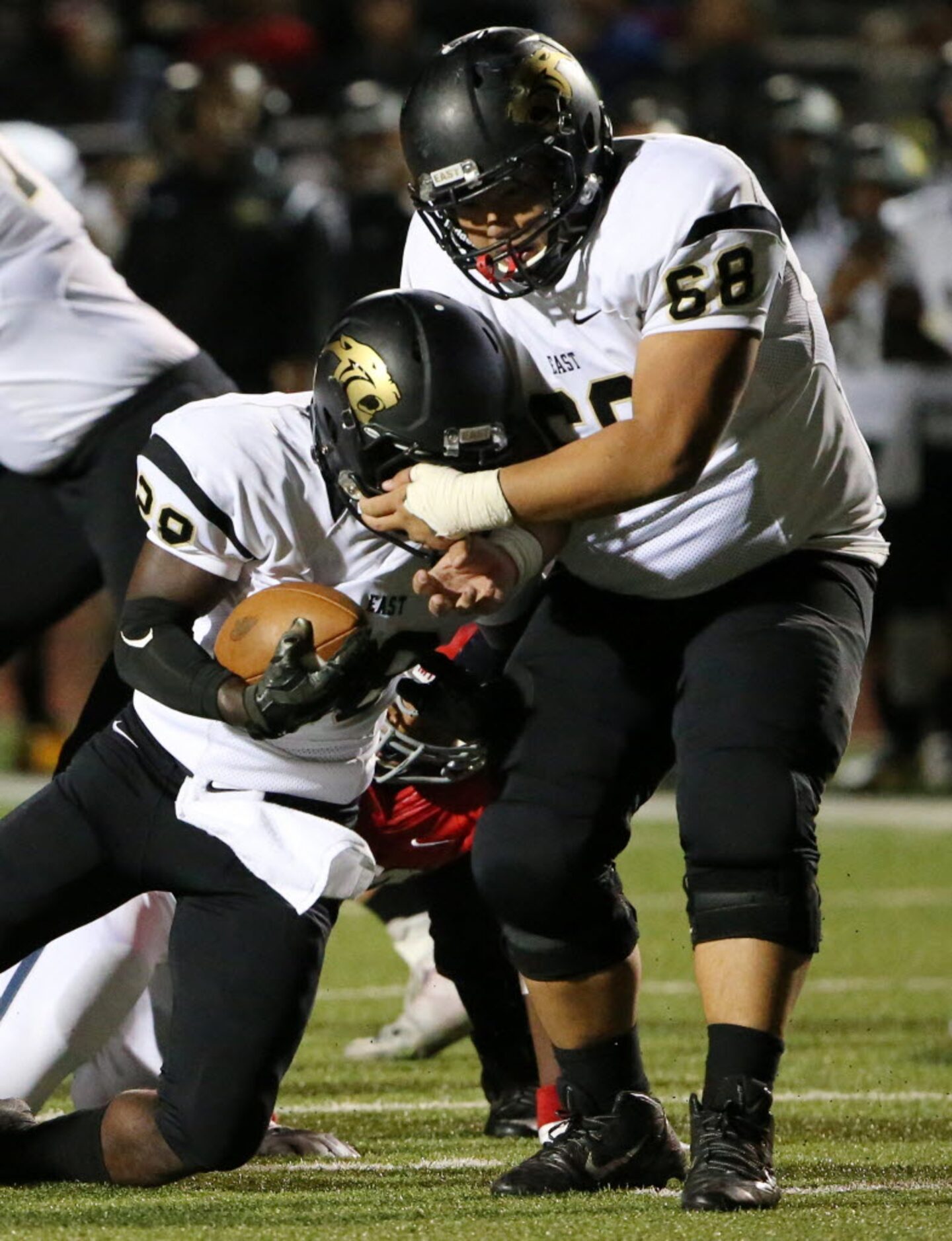 Plano East offensive lineman Cole Moore (68) pulls on the facemark of teammate running back...