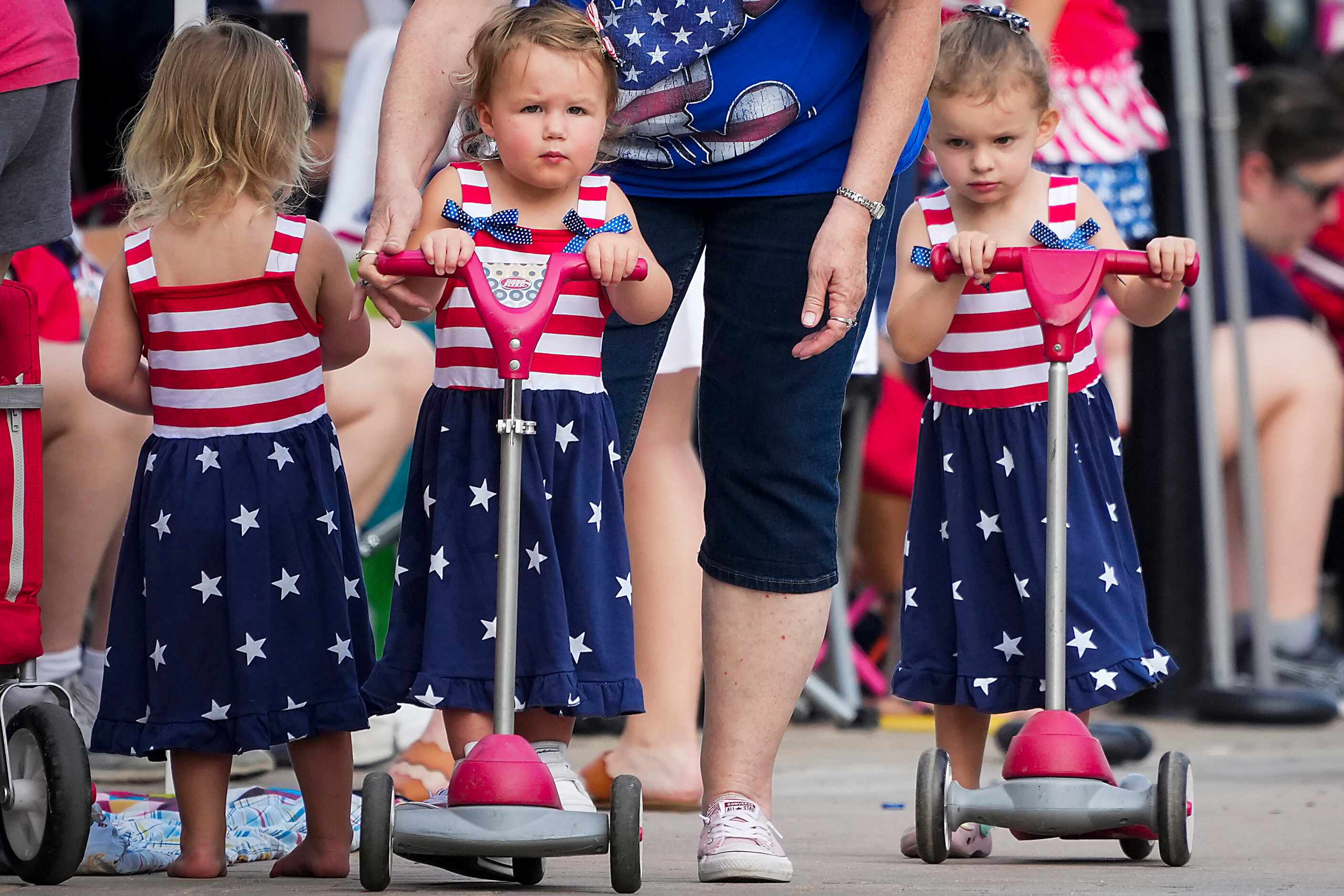 Brooklyn Kelsey, 2, (center) gets help riding a scooter from her grandmother as she plays...