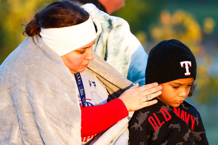 Nicole Scott (left), adjusts a beanie hat for her son Kaison, 6, (right) as they sit by...