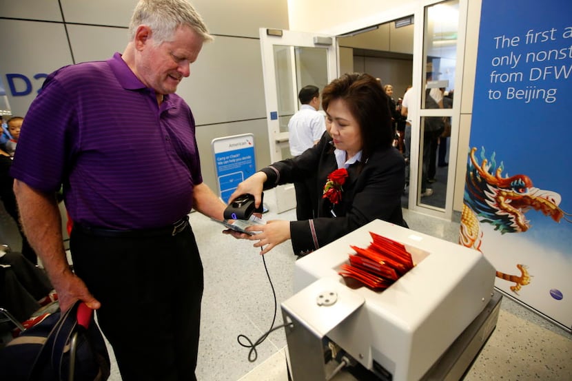 American Airlines ticket agent Jaime Chen (right) checks in one of the the first passengers...