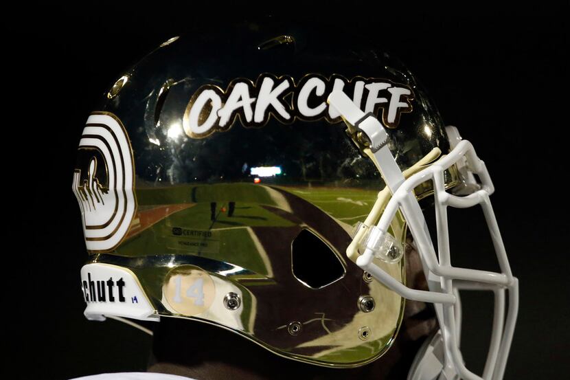 The South Oak Cliff players sport shinny gold helmets with the words Oak Cliiff of the side...
