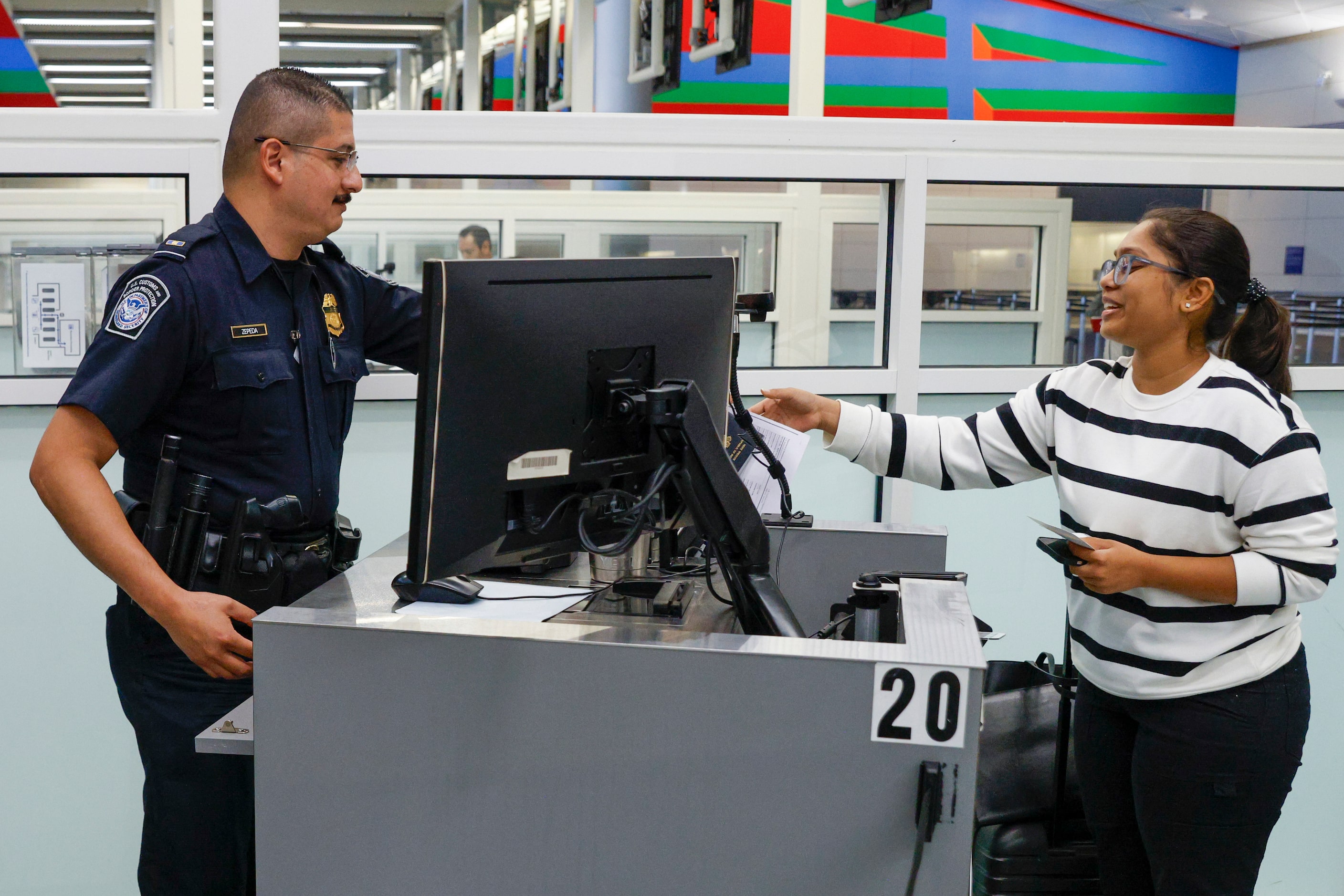 Customs and Border Protection officer Jose Zepeda hands Kusuma Pasupuleti of India her...