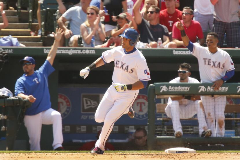 Texas' Alex Rios rounds first as the Rangers dugout celebrates his two-run triple in the...