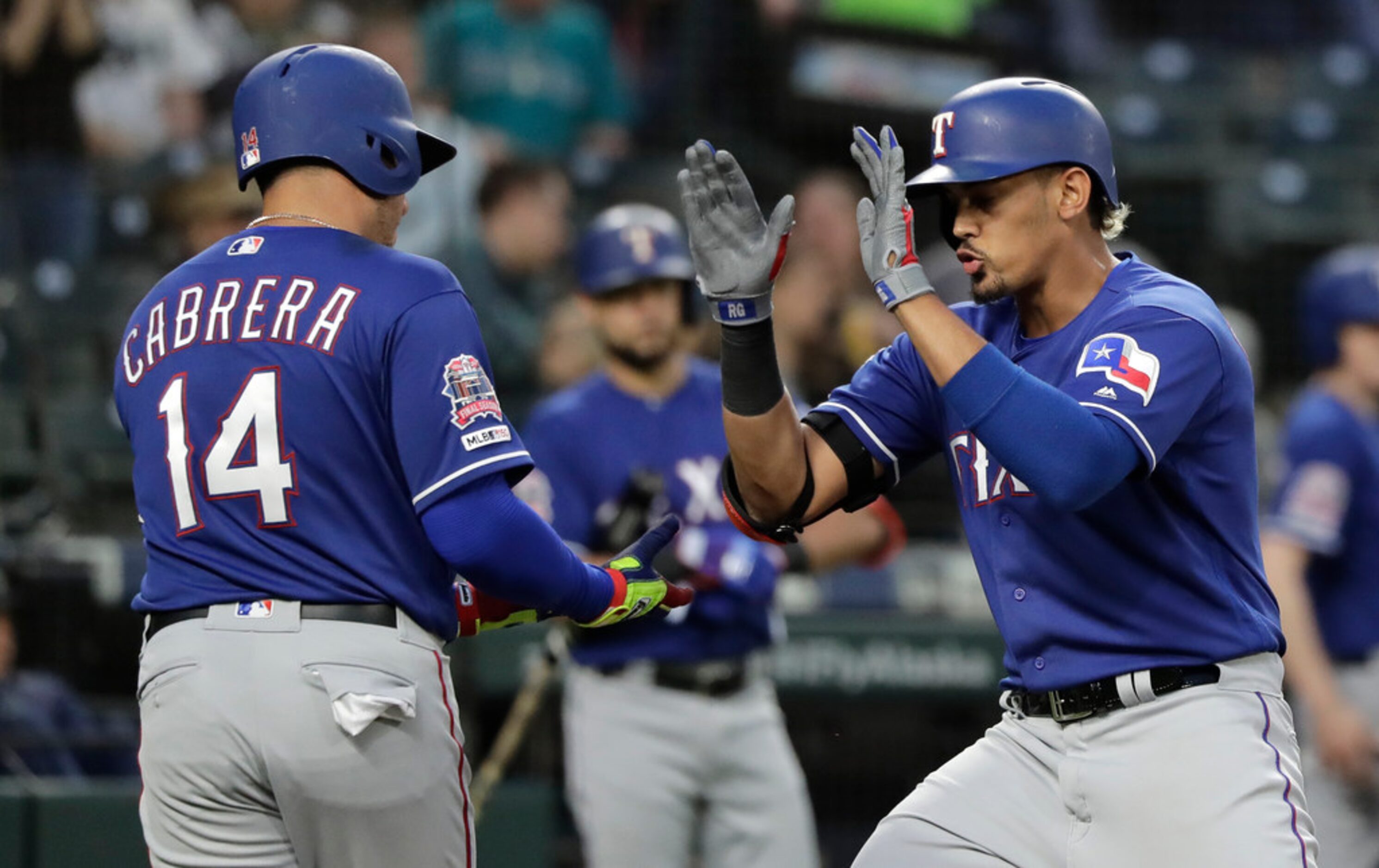 Texas Rangers' Ronald Guzman, right, is greeted by Asdrubal Cabrera (14) after Guzman hit a...