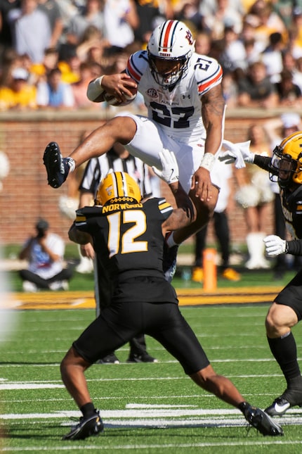 Auburn running back Jarquez Hunter, top, leaps over Missouri cornerback Dreyden Norwood...